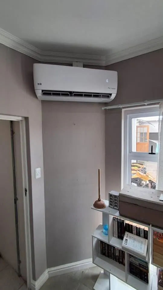 Wall-mounted aircon indoor unit in a living space with crown moulding