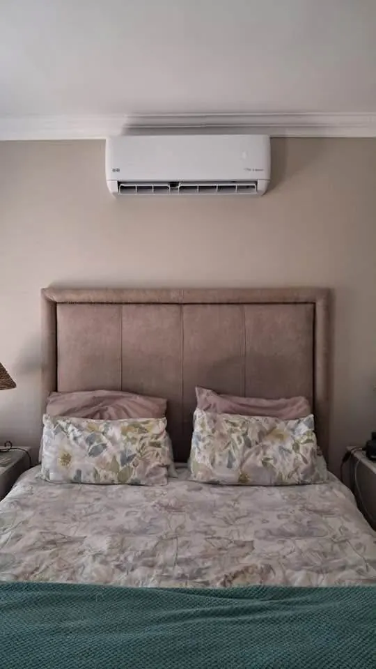 Aircon indoor unit mounted above a bed in a bedroom